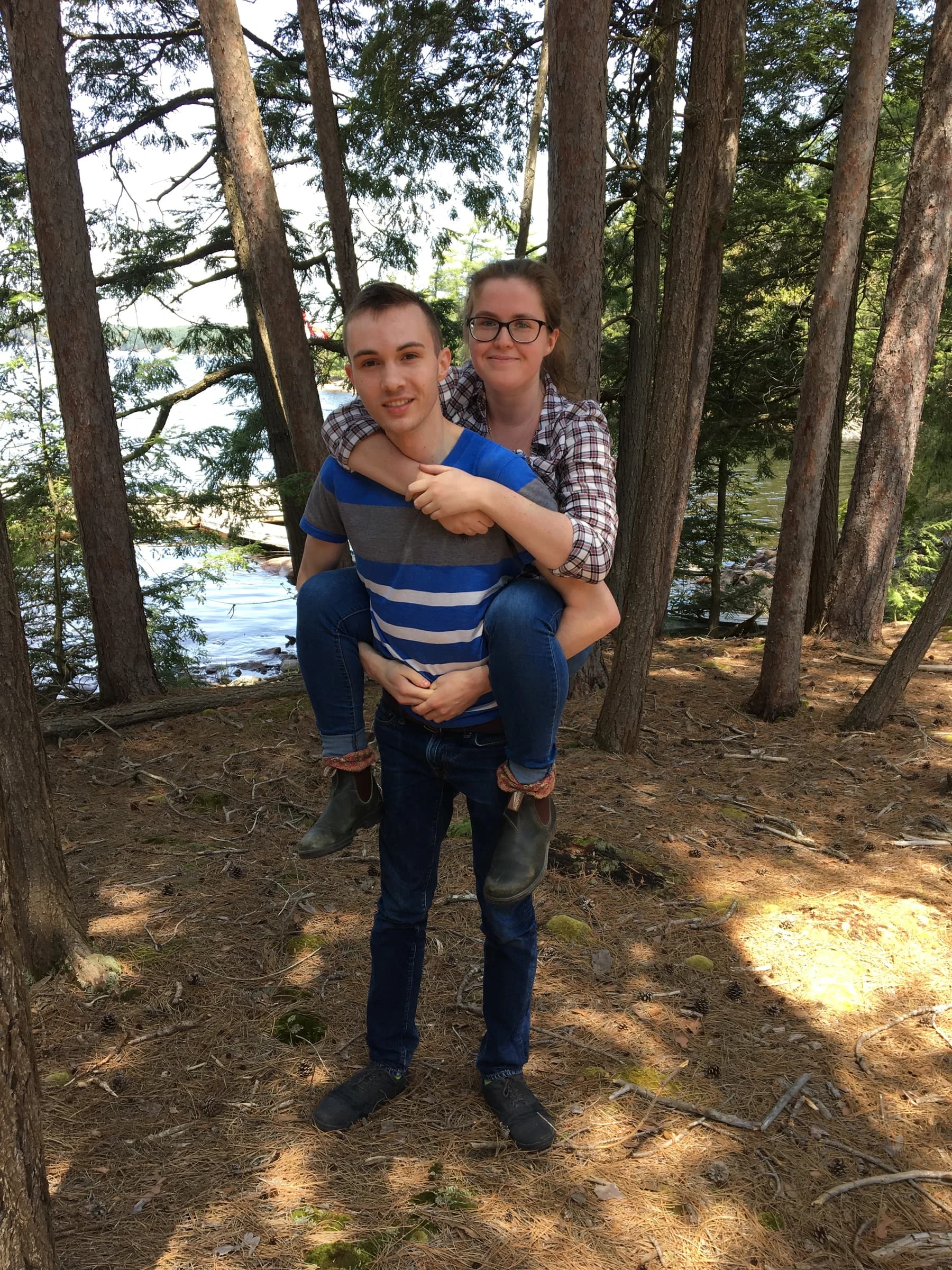 Rachel riding on Reid’s back in the woods near the cottage