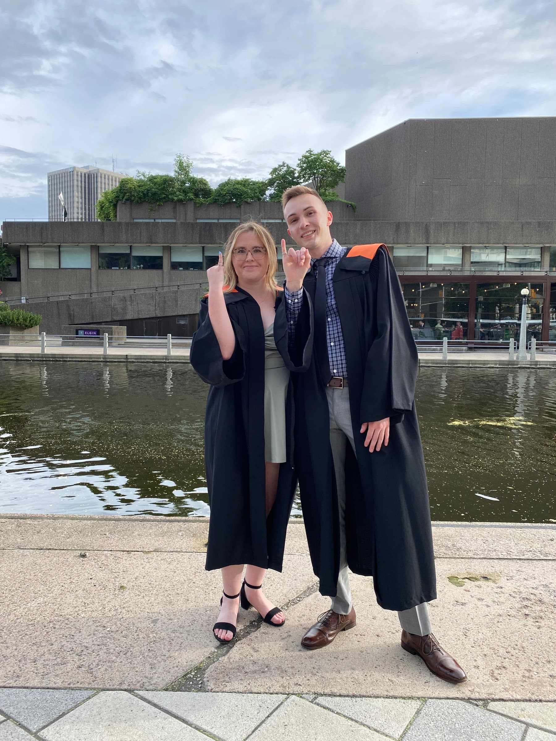 Rachel and Reid in graduation gowns beside the canal