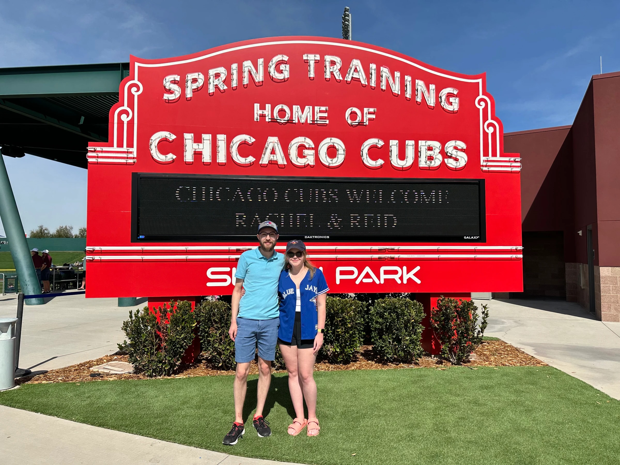 Rachel and Reid in front of the Sloan Park marquee reading Chicago Cubs Welcome Rachel and Reid